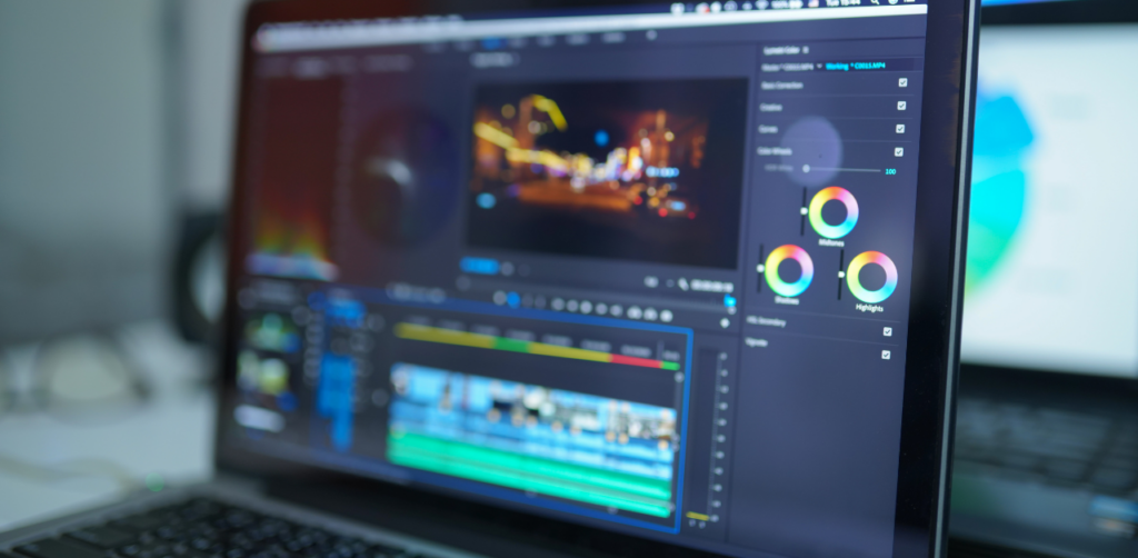 Close-up of a video editing software on a laptop screen, showing color wheels, a timeline, and a blurred video preview