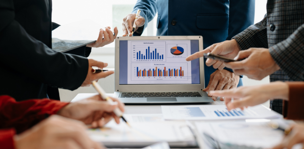 Group of professionals discussing charts and graphs displayed on a laptop during a business meeting