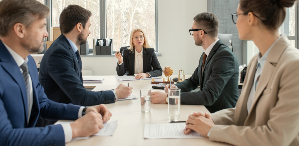 Business meeting with a woman leading a discussion at a table with four attentive professionals in formal attire