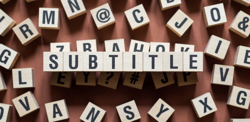 Wooden letter blocks spell SUBTITLE among scattered alphabet tiles on a brown surface