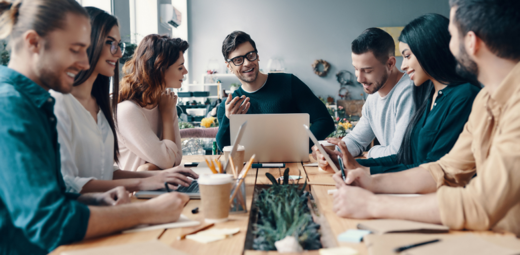 Group of young professionals gathered around a table, brainstorming and collaborating in a casual office