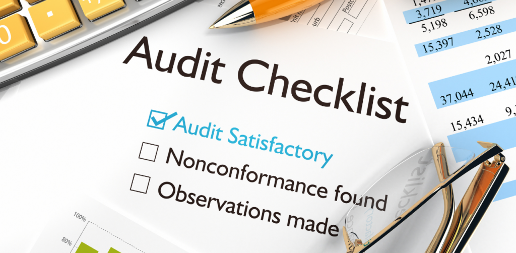 Audit checklist form with a blue checkmark beside Audit Satisfactory and financial documents nearby