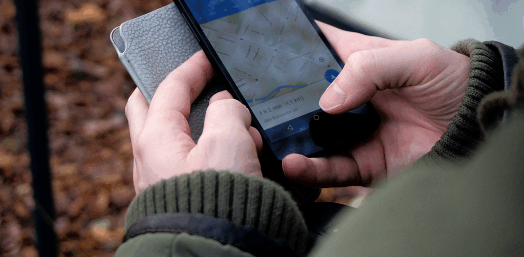 Close-up of hands holding a smartphone with a GPS map and route displayed